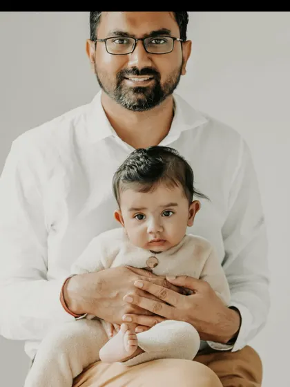A classic father and child portrait that speaks volumes. The direct, curious gaze of the baby combined with the father's gentle smile creates a beautiful connection. These are the simple, heartfelt images that families will look back on for years to come.
