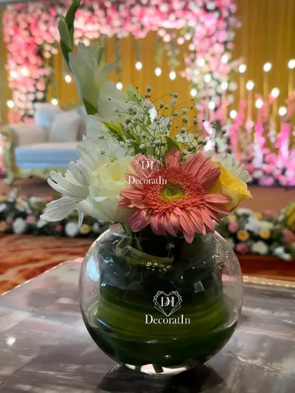 A simple yet elegant floral centerpiece in a glass bowl, used on guest tables to continue the floral theme of the engagement party.
