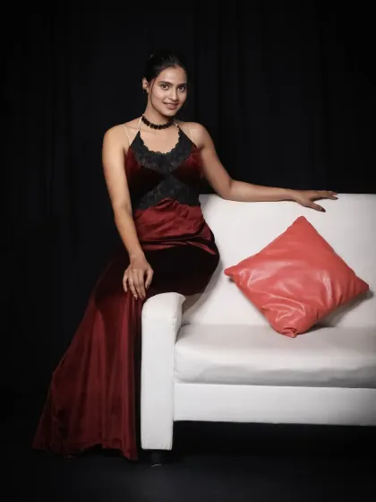 Our wine-red velvet bodycon dress is both elegant and alluring. It features delicate lace details and is shown here on our modern white sofa against a classic black backdrop.