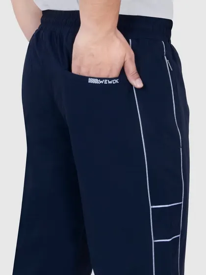 A close-up shot focusing on the pocket and logo detail of the sportswear pants, showcasing the quality and branding.