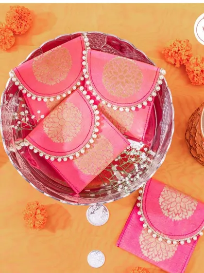 Celebrate your love with exquisite coin packaging. These vibrant pink pouches with pearl detailing are a beautiful way to present a traditional shagun coin.