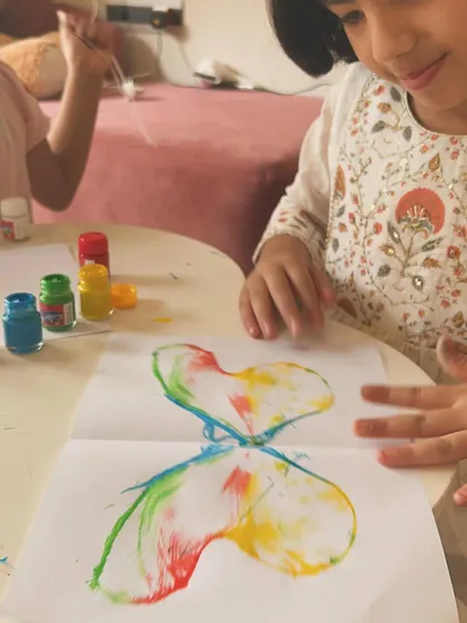 The moment of discovery. This little artist is amazed by the colorful butterfly print that appeared after pulling the paint-soaked rope.