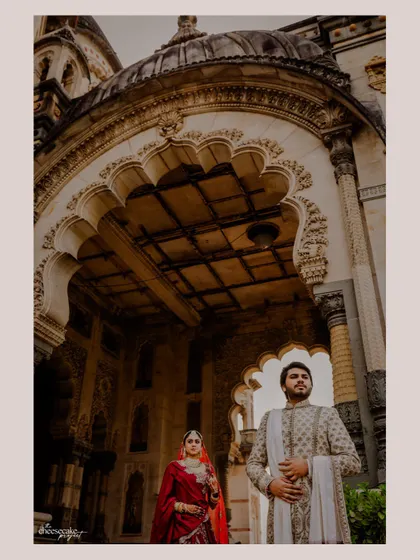 A creative shot looking up at the couple framed by the ornate ceiling of the palace.