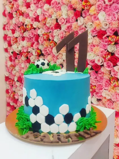 A simple and clean football-themed cake for an 11th birthday, with a hexagonal pattern on the side.
