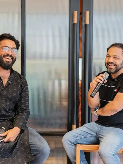 Two authors sharing a laugh on stage. We often invite fellow writers to host, fostering a sense of community and peer support.