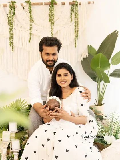 A sweet family photo where the parents' hands gently cup their newborn's face. This pose emphasizes how small and precious the baby is, creating a very tender portrait.
