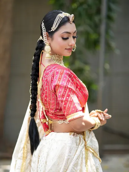 A side profile showcasing the beautiful braided hairstyle and the delicate details of the makeup. This look is a perfect blend of tradition and modernity.