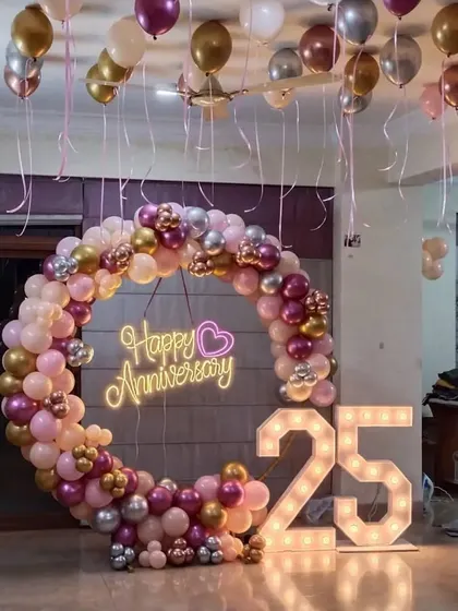 A beautiful 25th-anniversary party with a circular balloon arch in pastel pinks and metallics, and a '25' marquee light.