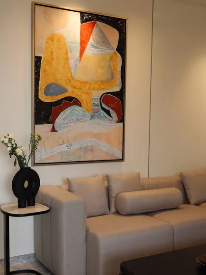 Art is often the soul of our spaces. Here, a large, vibrant abstract painting serves as the focal point, its warm colors complementing the neutral tones of the minimalist sofa and the sculptural black vase on the side table.