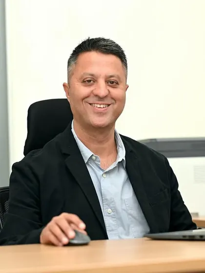 A friendly and approachable CEO portrait. Shooting in a modern office setting with a laptop makes the image relatable and showcases a hands-on leadership style.