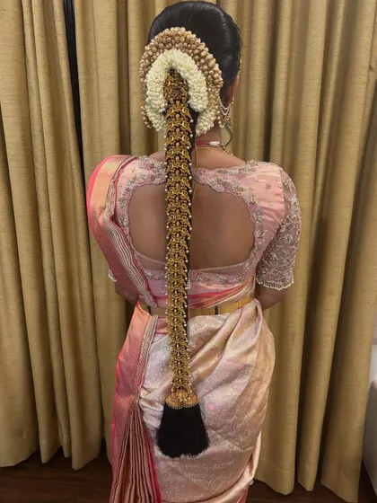 A classic bridal look featuring a full gold 'Jadai' over a neat braid, paired with a beautiful silk saree. This is a timeless choice for any South Indian bride.