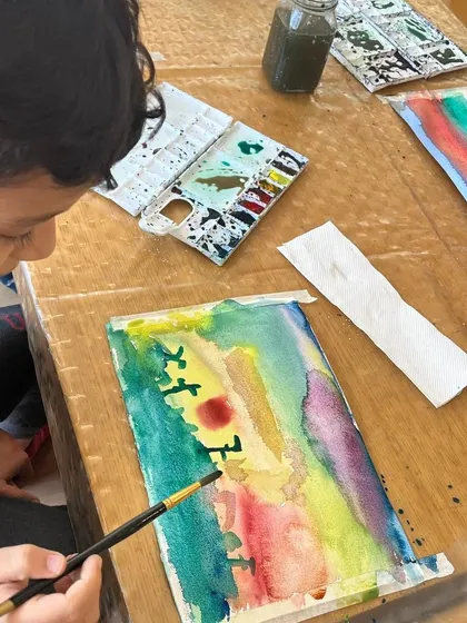 A duplicate of ID 119, showing a student's concentration as he adds details to his landscape.