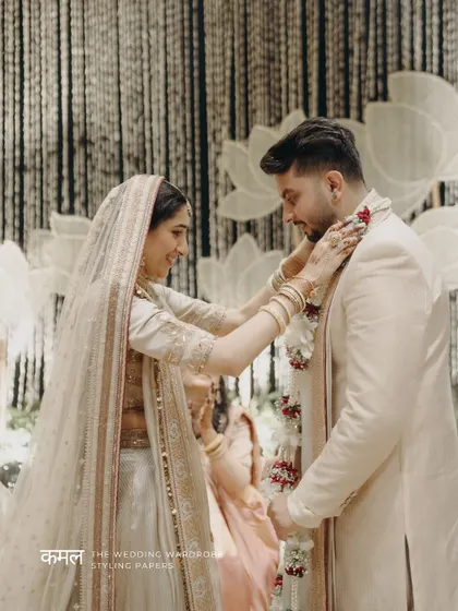 The couple during the 'varmala' ceremony, with the lotus-themed mandap decor visible in the background.