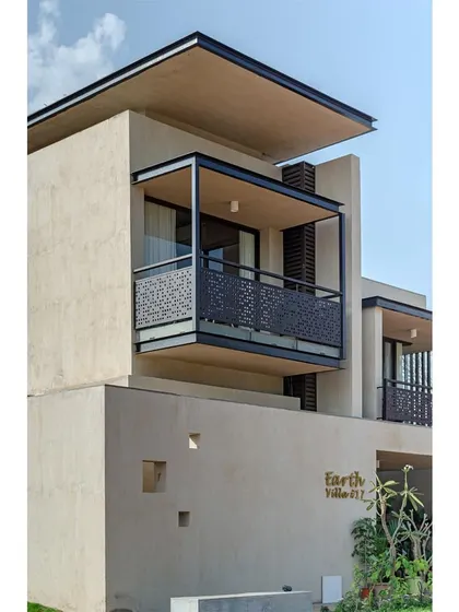 A detail of the villa facade, showing the perforated metal railing on the balcony. This element provides safety while allowing for views and light, adding a layer of texture to the elevation.