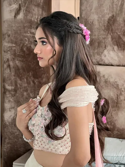 A beautiful profile shot of the client with her floral half-updo, showcasing how the style complements her off-shoulder blouse.