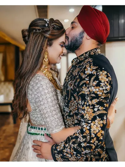 A tender and intimate moment between the couple. The groom's forehead kiss and the bride's happy, serene expression make this a beautifully emotional photograph.