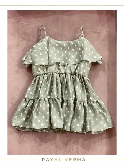 A flat-lay of the green ruffle floral dress. This view highlights the spaghetti straps and tiered design, perfect for keeping your little one cool and stylish.