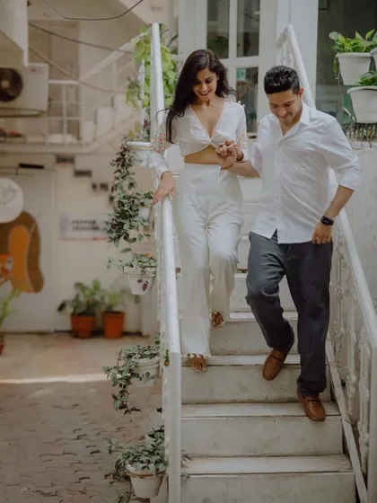 A happy, natural moment as the couple walks down the stairs hand-in-hand, sharing a smile during their pre-wedding shoot.