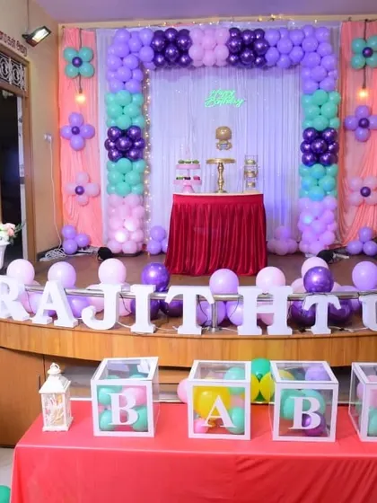 A sweet and simple first birthday setup in pastel purple, pink, and mint green. The column-style balloon arch and "BABY" blocks create a lovely backdrop for a smaller celebration.