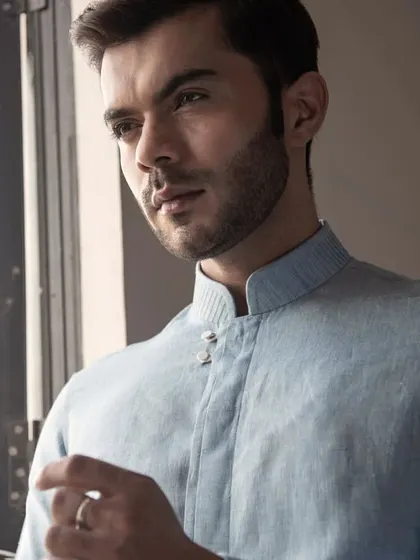 A portrait of a model in the blue linen shirt, capturing its effortless summer elegance.