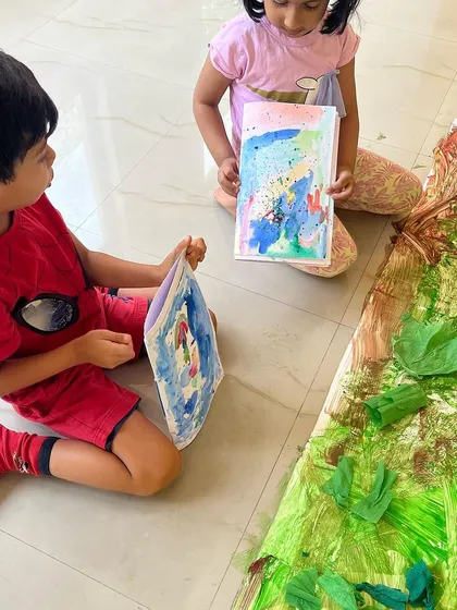 Sharing and discussing their artwork is a key part of the creative process. Here, two children show each other their creations, building communication skills and confidence.
