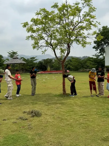 A group of young explorers works together on a rope-based team challenge. Activities like this teach the fundamentals of teamwork and mutual support.