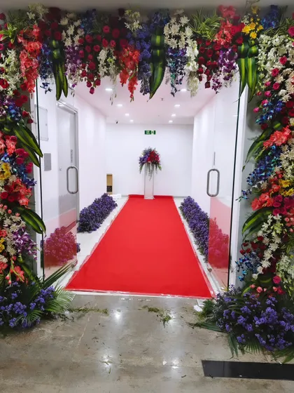 This view shows how a floral arch and red carpet can transform a simple hallway into a grand entrance for an office opening. The arrangement guides guests into the main event space.