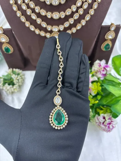 Our multi-layered Rani Haar sets are a bestseller. This piece showcases six layers of uncut Polki-style stones with a stunning emerald green pendant and matching earrings, offering a truly royal look for weddings and grand occasions.