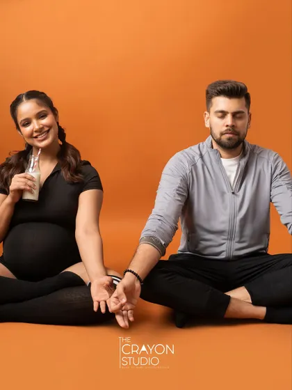 Finding balance together. This meditative pose, with a playful twist as she sips her drink, is a fun way to show their partnership during the pregnancy.