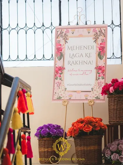Welcoming guests to a vibrant Mehendi with colorful floral arrangements in rustic baskets and a beautifully designed sign. The stairs were decorated with bright tassels, setting a festive mood from the moment guests arrived.