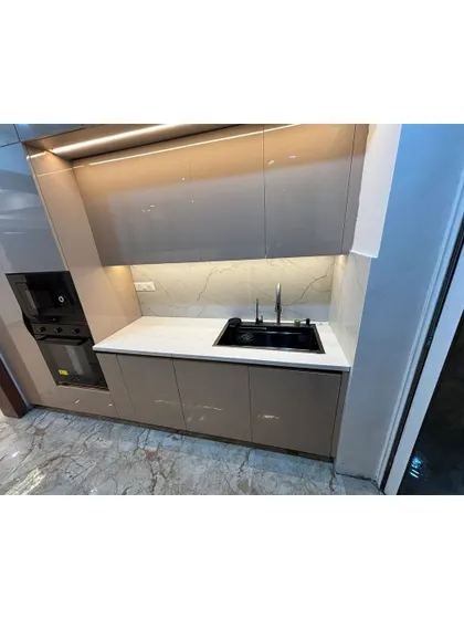 A compact and efficient kitchen pantry or dry kitchen area. The glossy cabinets and built-in oven demonstrate how we can create functional zones even in smaller spaces.