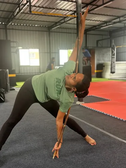 Using a staff for assistance, this student works on a triangle pose stretch. Tools can be very helpful for improving flexibility and alignment.