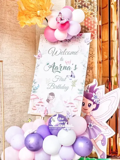 The full welcome easel display, featuring the custom sign, a fairy cutout, and a cascade of balloons, setting the perfect tone for a magical first birthday.