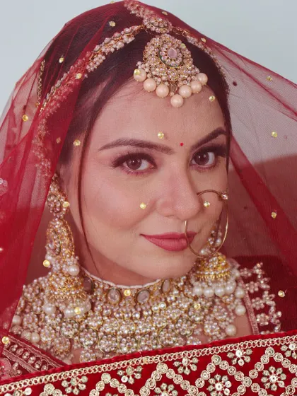 A different bride with a classic look, featuring a pearl-encrusted matha patti and a bold red lip.