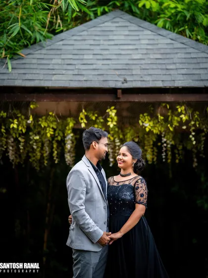 A classic couple's portrait taken in front of a dark, rustic gazebo.
