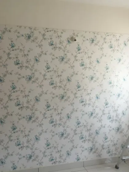 A light and airy floral wallpaper with a delicate blue and green pattern. This is during the installation process, showing the clean application.