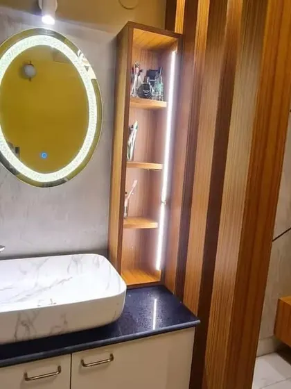 A close-up of a wash basin and vanity unit elegantly placed in the dining area of a Kolkata home, complete with a backlit mirror and storage.