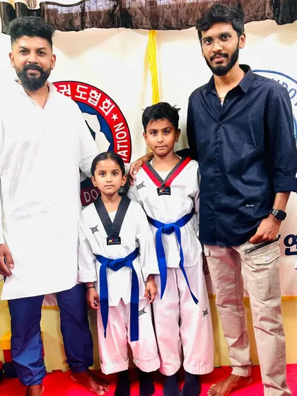 Two young students with their new blue belts, pictured with their coaches.