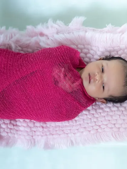 Pretty in pink. We use soft, stretchy wraps to keep newborns feeling secure and snug during their photoshoot, resulting in these adorable, peaceful portraits.