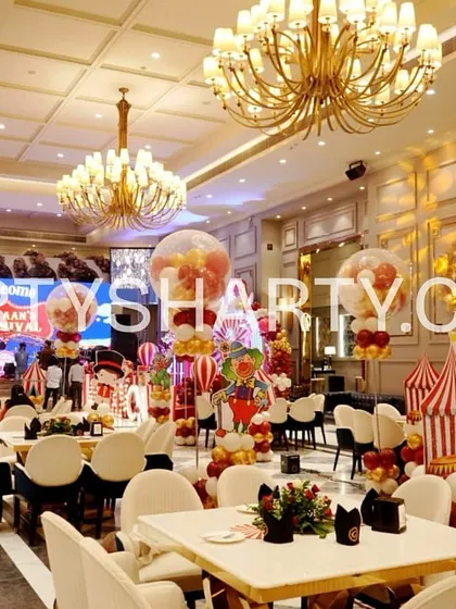 A wide-angle view of a carnival-themed party, showing the complete venue transformation with themed centerpieces, backdrops, and guest seating.