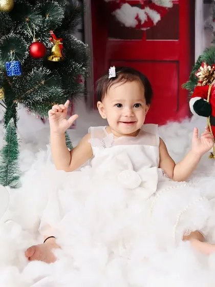 A joyful shot from a Christmas-themed first birthday, with the little girl clapping her hands in excitement.