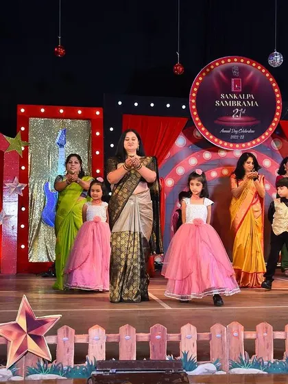 The children on stage in their beautiful pink and yellow gowns, taking a bow with their teachers after a successful performance.