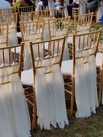 Simple and elegant chair decor for a ceremony. We used flowing white fabric to drape the gold chiavari chairs, creating a clean and sophisticated look.