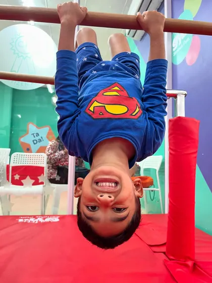Our very own superhero, hanging upside down with a huge grin. This is the look of a child who is confident, strong, and having the time of his life.
