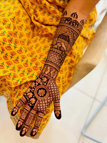 A close-up of a single arm, featuring a peacock in a jharokha and a lotus mandala on the palm.
