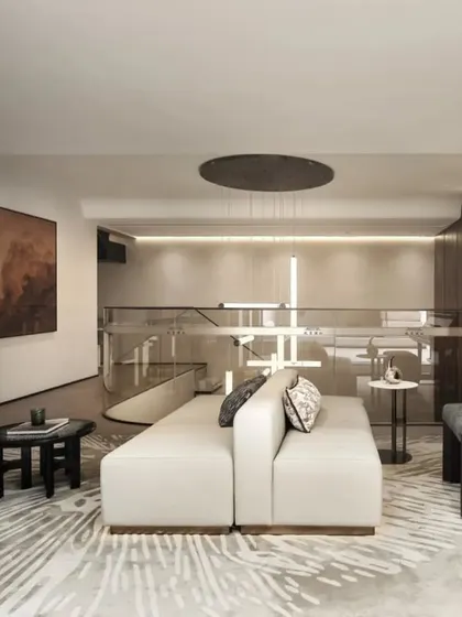 This view of a minimalist living area highlights a calm, neutral color palette and an open-plan layout. The design connects two levels with a glass balustrade, creating a sense of spaciousness while maintaining a sophisticated and comfortable atmosphere.