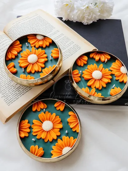A trio of my stunning Daisy Urlis. The vibrant orange daisies really pop against the emerald green wax base, and the scent of jasmine and ylang ylang fills the room.