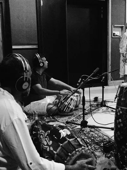 A black and white shot of me singing while the percussionists listen intently. This captures the dynamic of a live recording session, where we all feed off each other's energy.