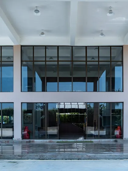 A direct look at the expansive glass facade of the Konark Academy lobby. This design choice floods the interior with daylight and creates a visual connection with the outdoors, reflecting a philosophy of open and transparent learning.