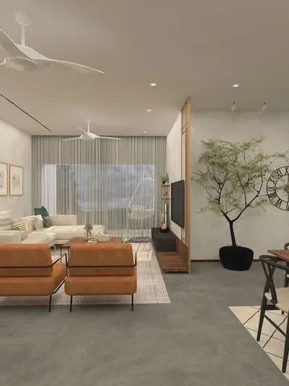 An open-concept living and dining area designed with a modern tropical aesthetic. The concrete-finish floor, light wood tones, and minimalist furniture create a clean, cohesive look. The indoor tree serves as a natural divider and focal point.